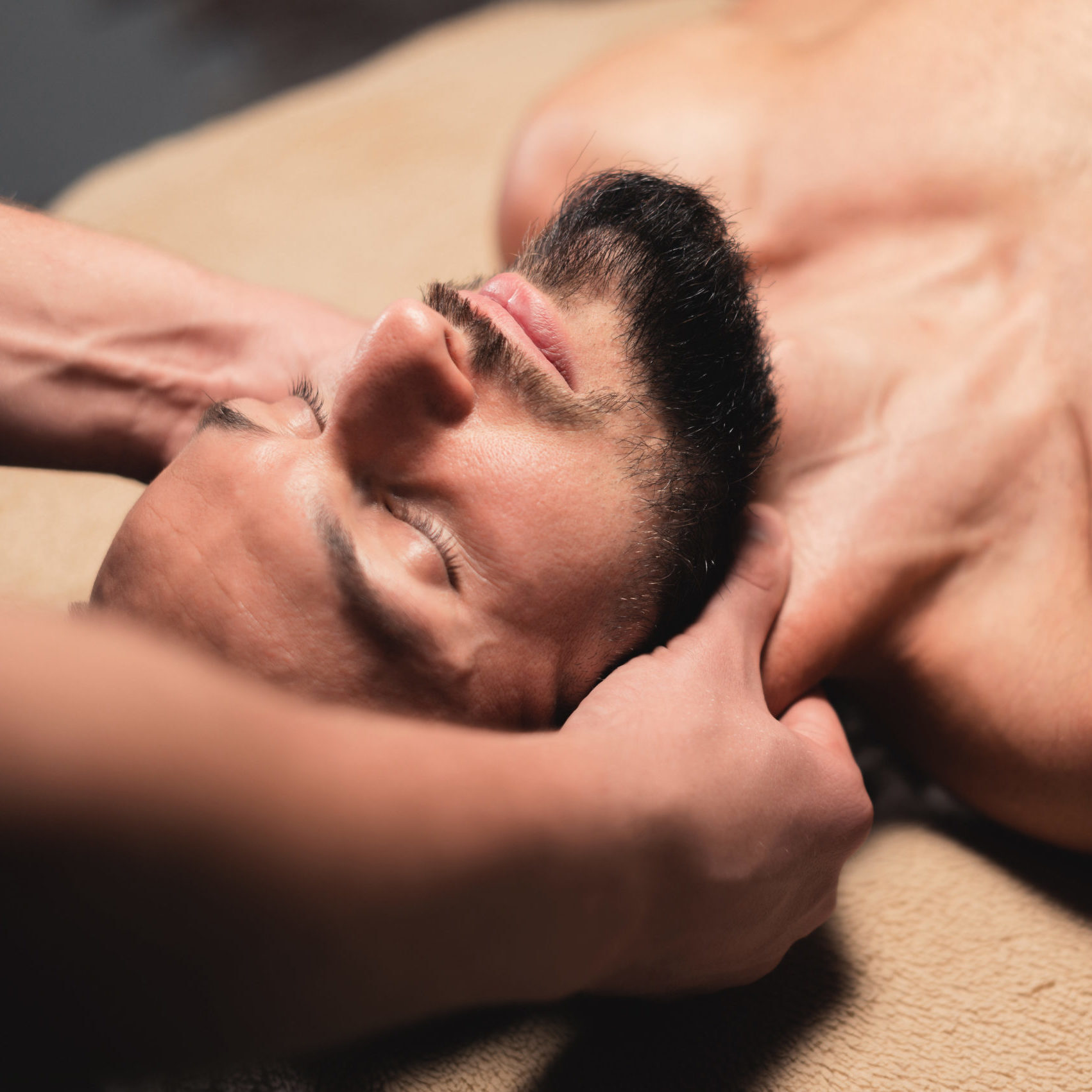 In a professional massage parlor, a Caucasian male athlete with a beard is kneading the neck. Sports massage of the lateral longitudinal muscles of the neck.